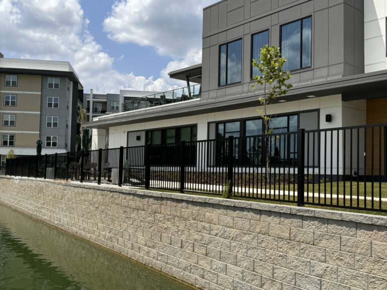 Modern black metal fence surrounding a contemporary apartment complex.
