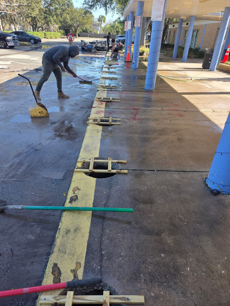 Workers installing bollards at parking area, outdoor scene.