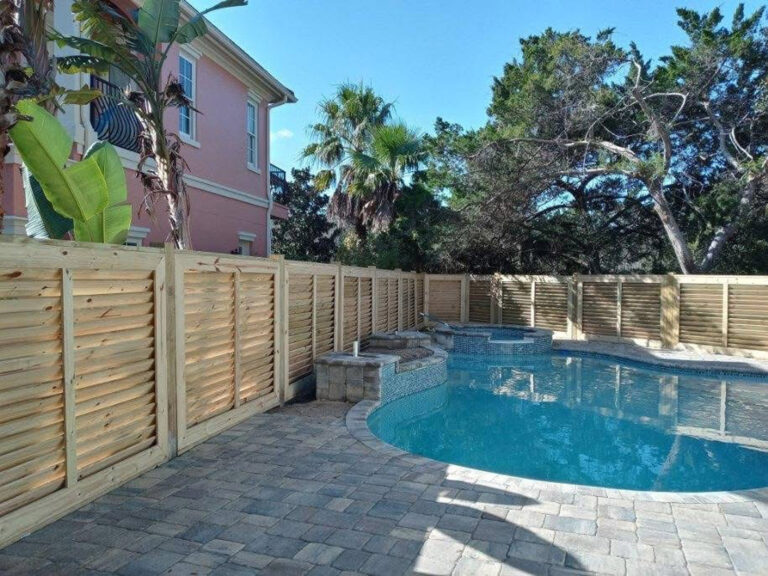 Wooden privacy fence around backyard pool.