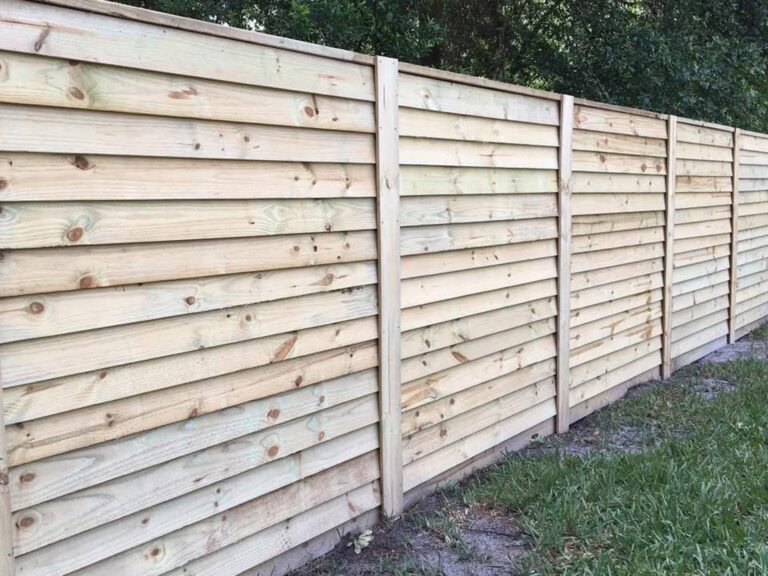 Wooden privacy fence installation with horizontal planks and sturdy vertical supports.