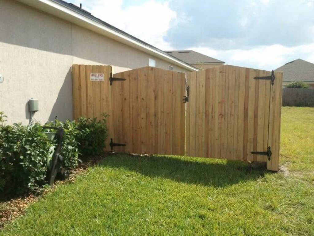 Wood privacy fence with black metal hardware installed on a residential yard.